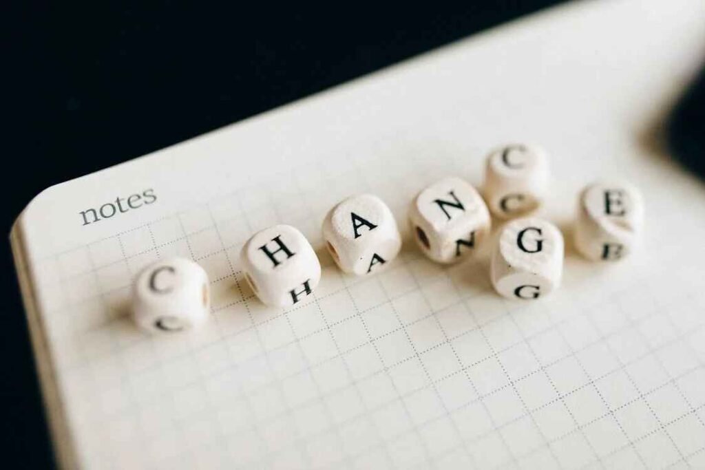 Wooden lettered blocks spelling the word "CHANGE" placed on a notebook, symbolizing the mindset shift needed to change spending habits and improve financial behavior.