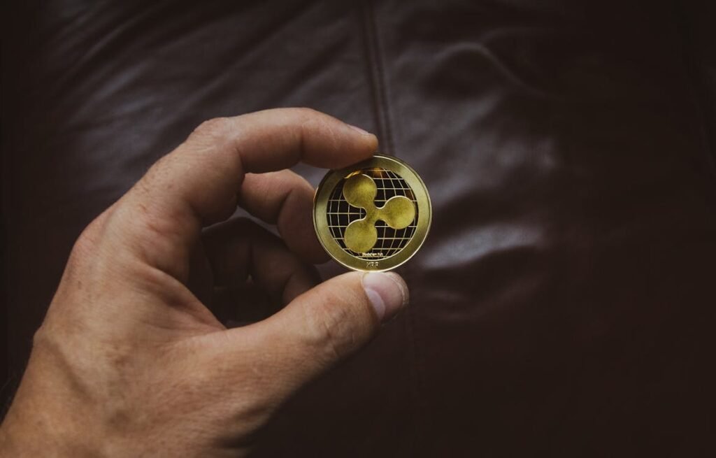 Hand holding a gold Ripple cryptocurrency coin, symbolizing modern investment gifts and digital asset opportunities.