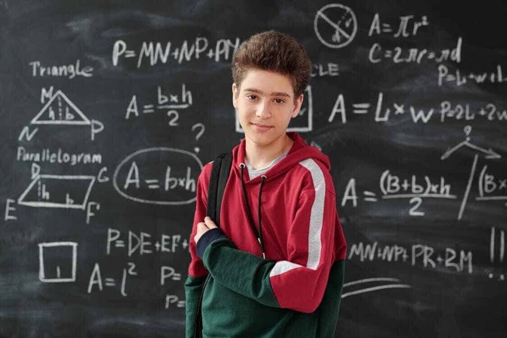 Confident high school student in front of a chalkboard filled with math formulas, representing focus and discipline—key traits for budgeting scenarios for high school students.