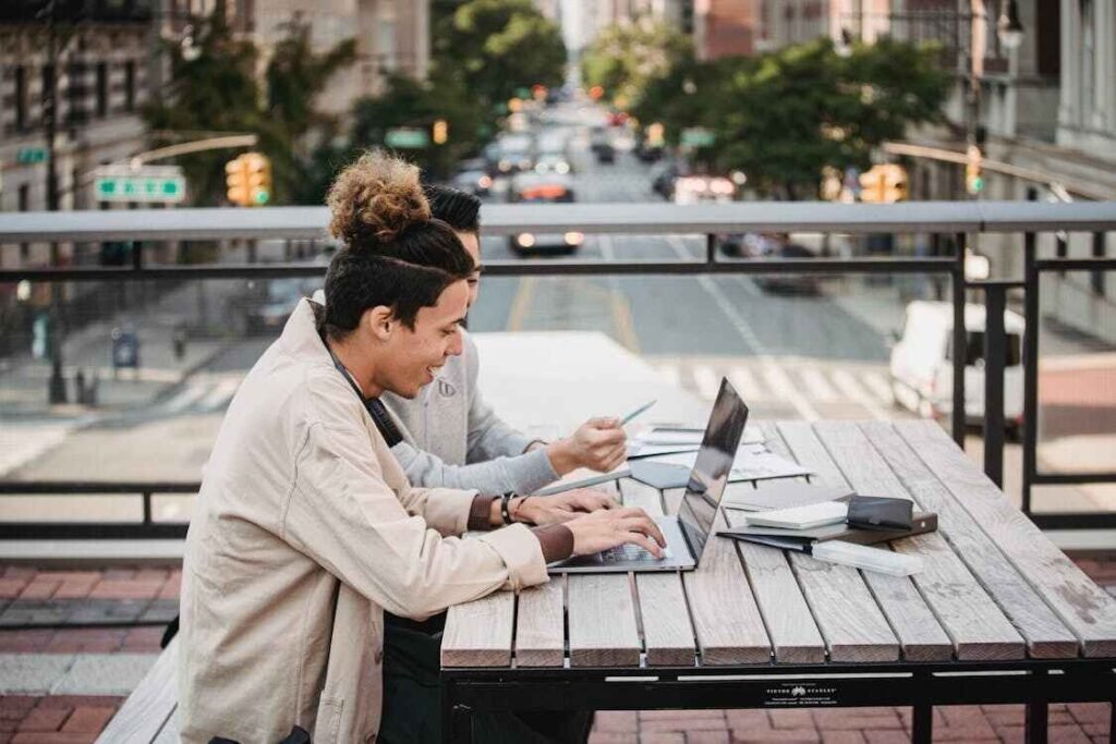Two high school boys are using the laptop while sitting in a cafe and look happy as they got this laptop from a student discount, symbolizing the importance of discounts as a budgeting scenario for high school students.