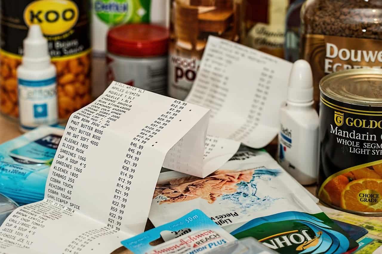 "Receipts and various grocery items scattered on a table, symbolizing daily spending. This image highlights the importance of changing spending habits, where small, mindful adjustments to everyday purchases can lead to significant savings over time."