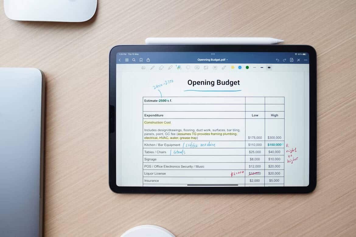 "An iPad displaying an 'Opening Budget' document with an estimate of 2500 square feet. The budget includes various expenditure categories such as construction costs, kitchen/bar equipment, tables and chairs, signage, POS systems, and liquor license. Low and high estimates are listed for each category. A detailed view of the document also includes handwritten notes on coffee machines and potential cost adjustments. This image is relevant for anyone researching best budgeting apps for teens, as it exemplifies managing and tracking expenses for a project."