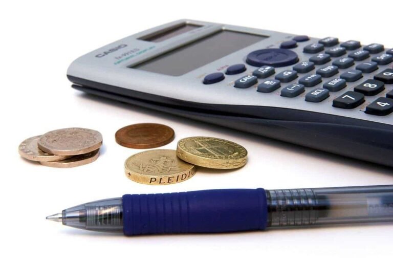 Calculator with coins and pen symbolizing the importance of creating a realistic budget to avoid common budgeting mistakes.