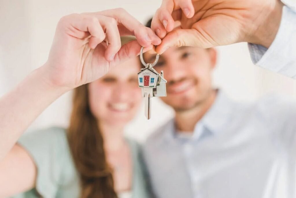 "Couple smiling while holding a key with a house-shaped keychain labeled 'HOME', symbolizing the motivation for paying yourself first regularly to eventually own a home."
