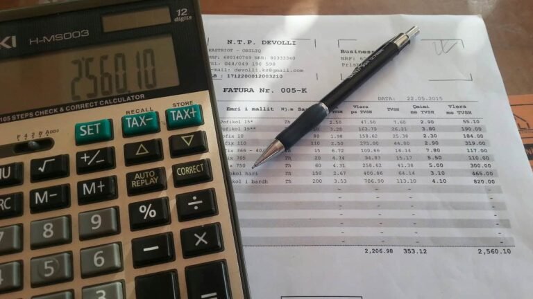A close-up of a calculator showing a total of 2560.10 placed next to an invoice and pen, highlighting the importance of calculating expenses—because the first priority in your budget should be essential financial planning.