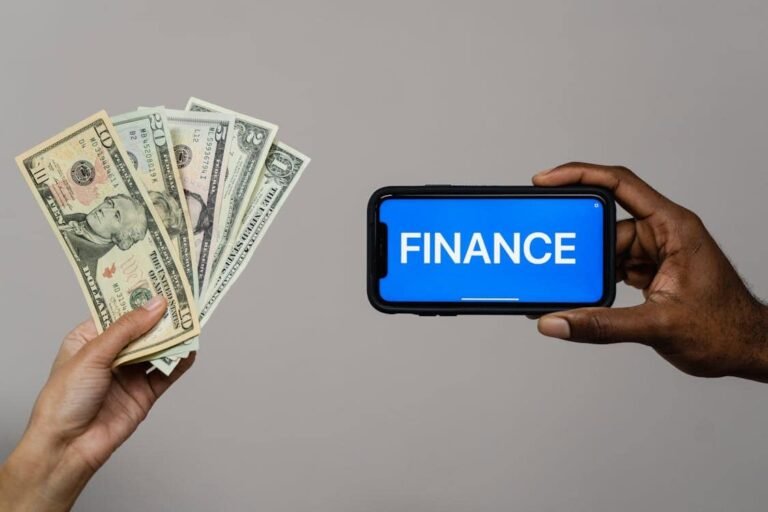 "One hand is holding several bills, while another holds a smartphone displaying the word 'FINANCE.' This visual emphasizes the relationship between money management and the essential skills needed for budgeting for life after high school."