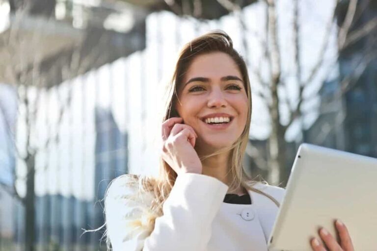 Smiling teen girl holding a tablet and talking on the phone, representing budgeting help for teens with digital tools and personal support.