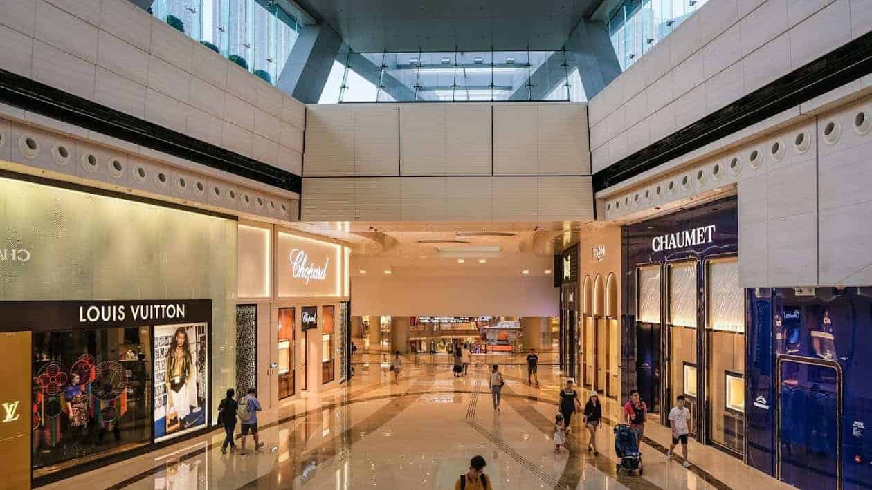 Teenagers walking through a luxury shopping mall, highlighting spending choices and financial decisions, representing the question of how unnecassary spending can spoil the plan of saving money for a house while renting