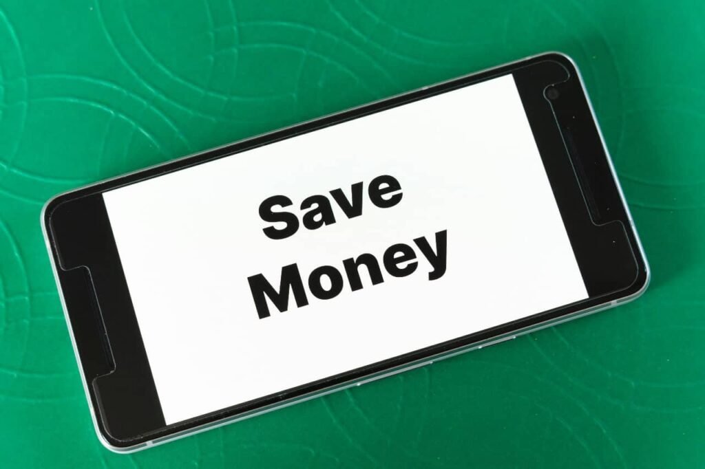 A smartphone on a green surface displays the bold message “Save Money,” emphasizing the core principle of the no spending challenge—cutting unnecessary expenses and being intentional about every dollar spent.