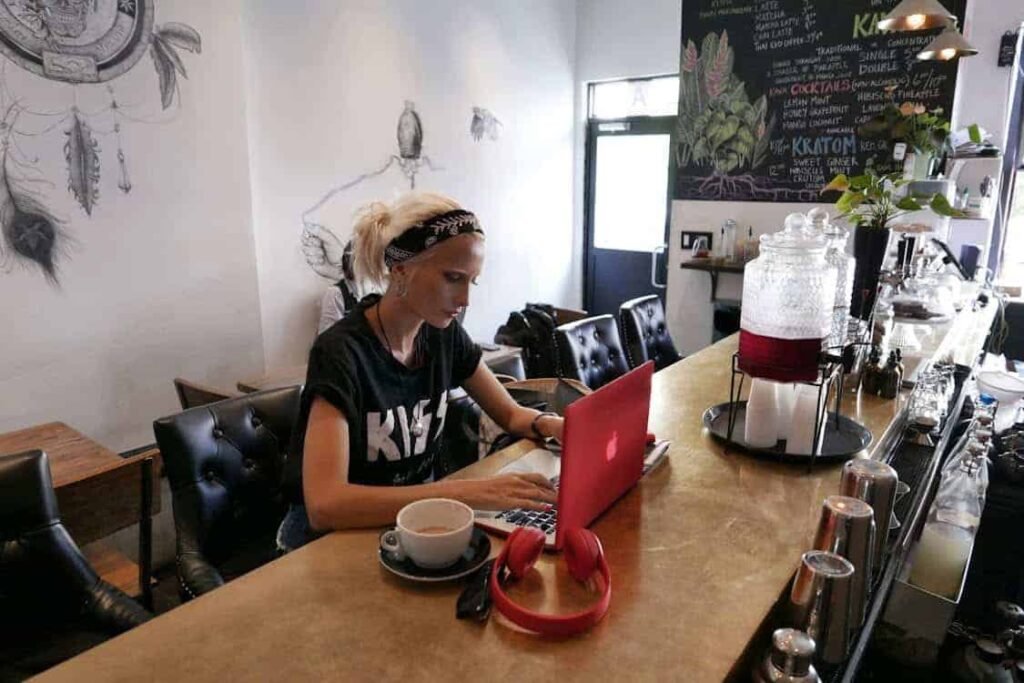 Young woman working on laptop in a café, focusing on online income skills for teens and money management