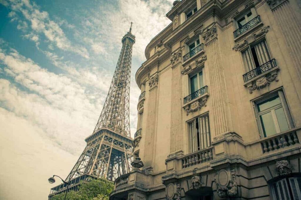 The Eiffel Tower is visible behind a classic Parisian building, suggesting a teenager's dream of saving up for a trip to Paris.