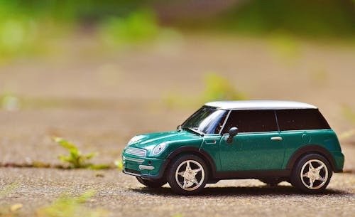Green toy car symbolizing how to save money for a car.