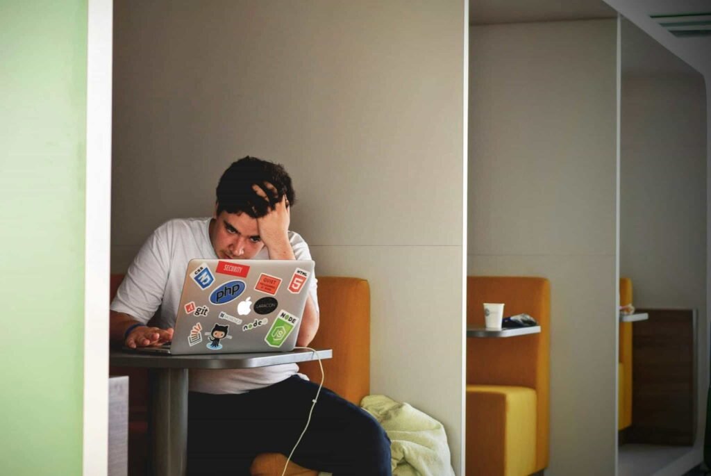 A relatable photo of a teen feeling stressed while working on a computer, illustrating the challenges of getting started with budgeting tips for teens and financial planning