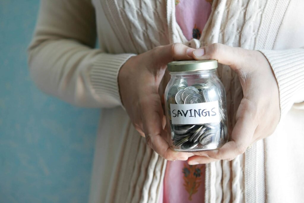 Visual representation of budgeting tips for teens, with a person holding a jar labeled 'SAVINGS,' highlighting the importance of setting money aside for future goals.