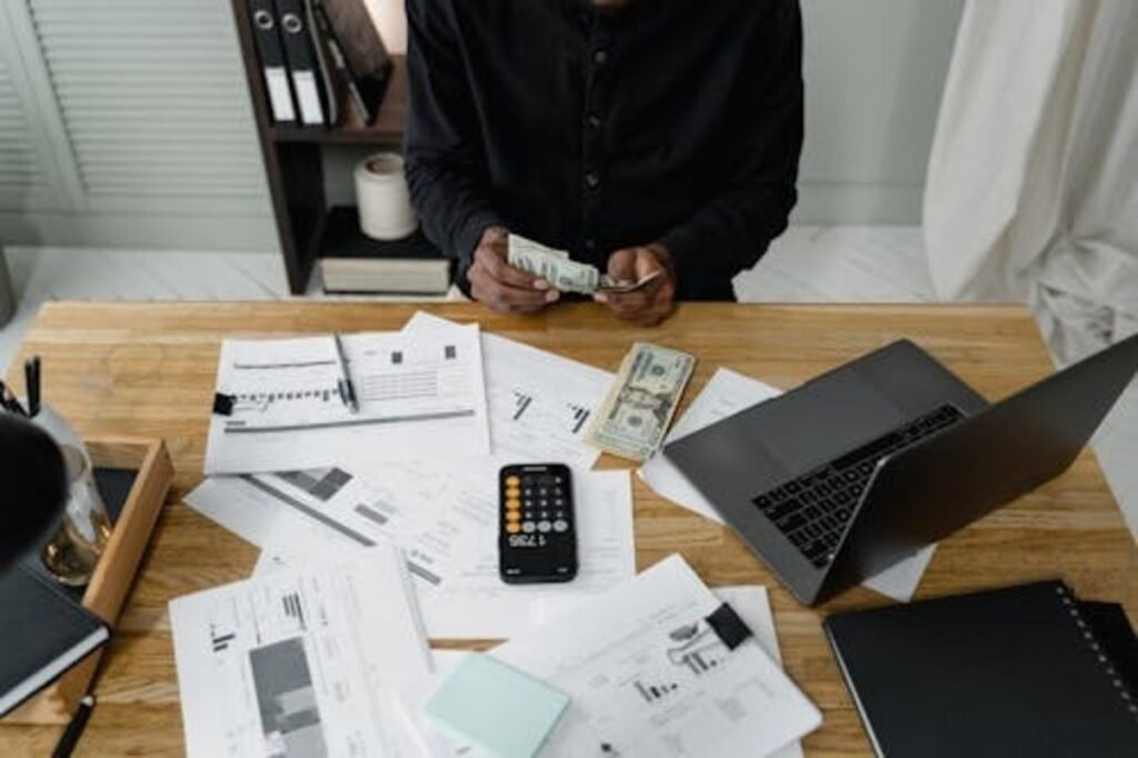 investor counting money with financial documents and calculator on desk