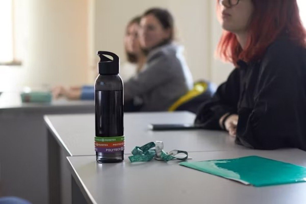 Black reusable water bottle on classroom desk — sustainable hydration and practical gift idea for college students.
