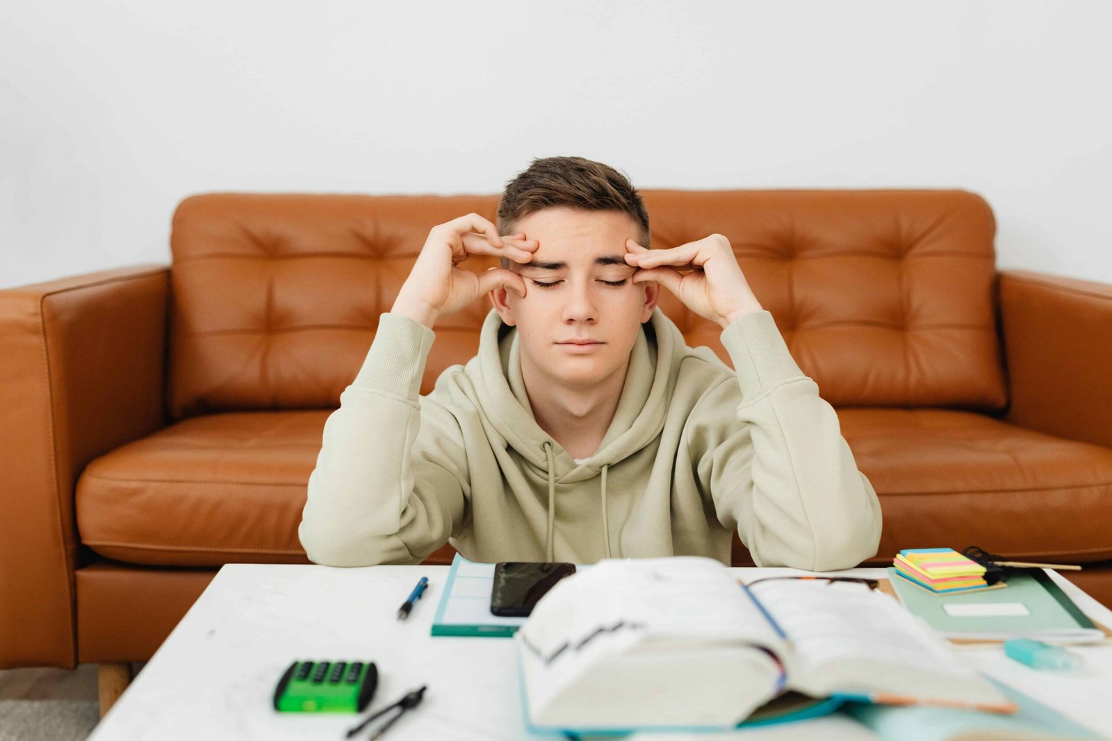 Stressed student sitting at desk with open books and bills, worried about how to get out of private student loans.