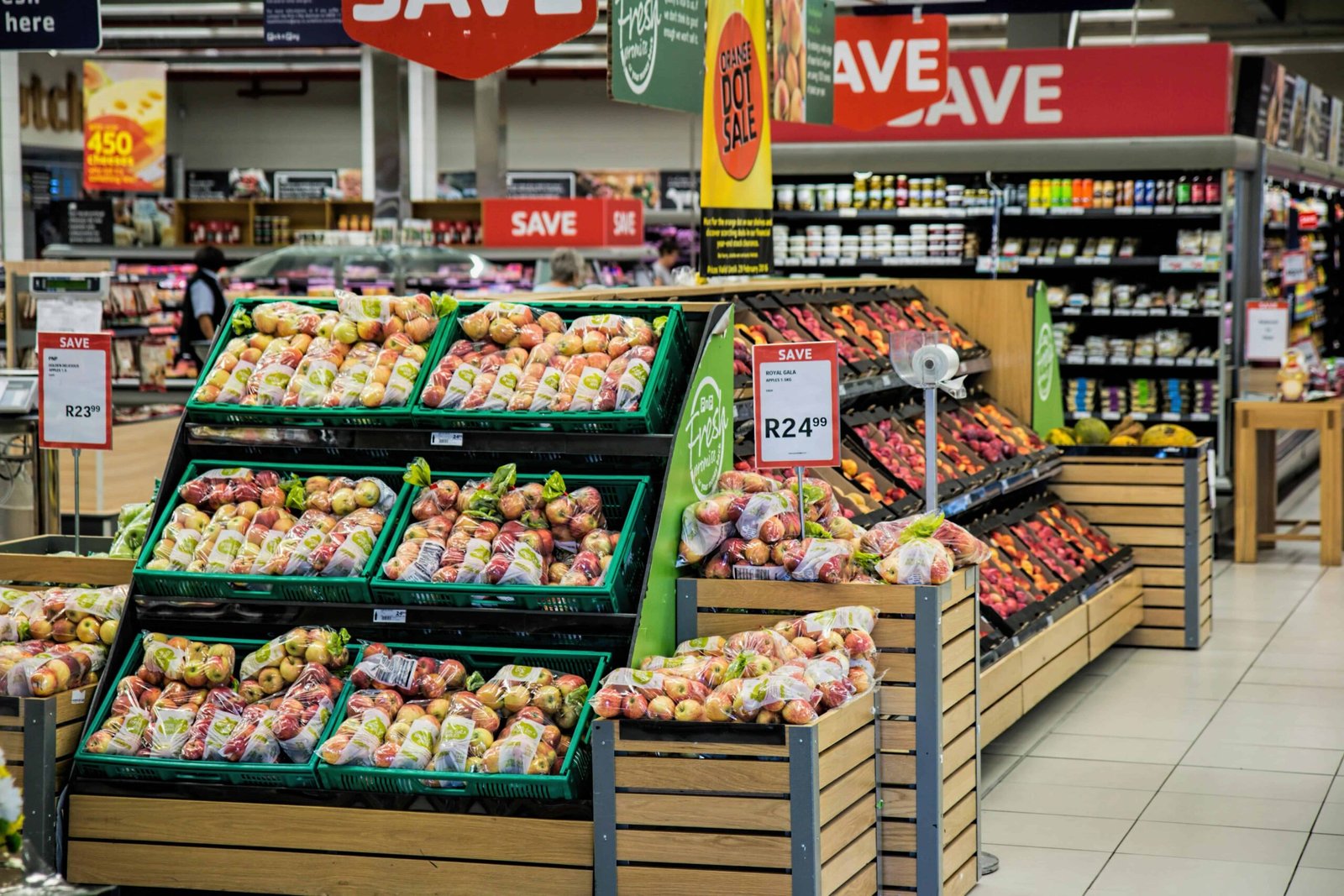 Supermarket produce section with fresh apples and SAVE signs highlighting student grocery budgeting tips